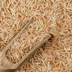 Detailed close-up of organic brown rice grains with a wooden scoop showcasing texture and natural colors.